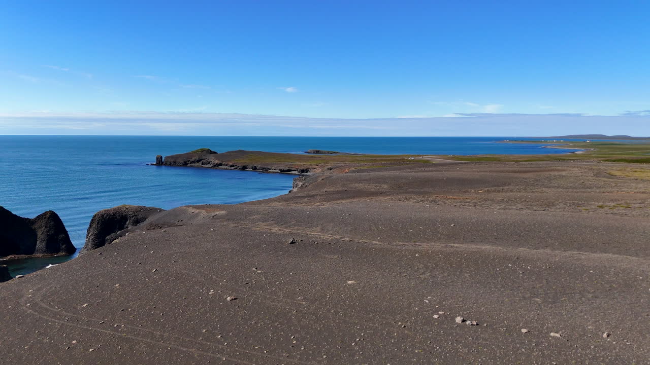Aerial view of Kópasker coastline with a natural rock arch, showing rugged shorelines, ocean waves, and raw northern Iceland scenery under bright daylight