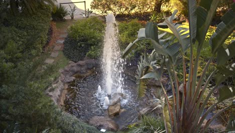 small water fountain in front of a shopping center surrounded by abundant vegetation, creating a feeling of tranquility