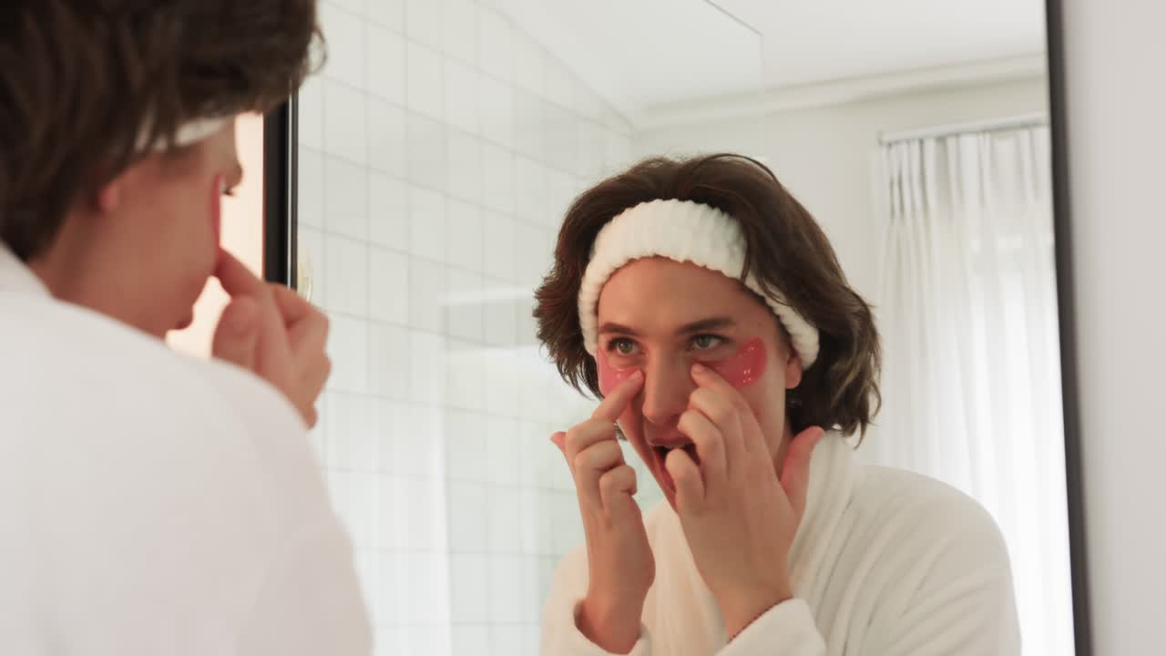 Donna che si guarda allo specchio del bagno, applicando patch di idrogel per l'idratazione