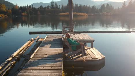 man sitting on dock at sunset