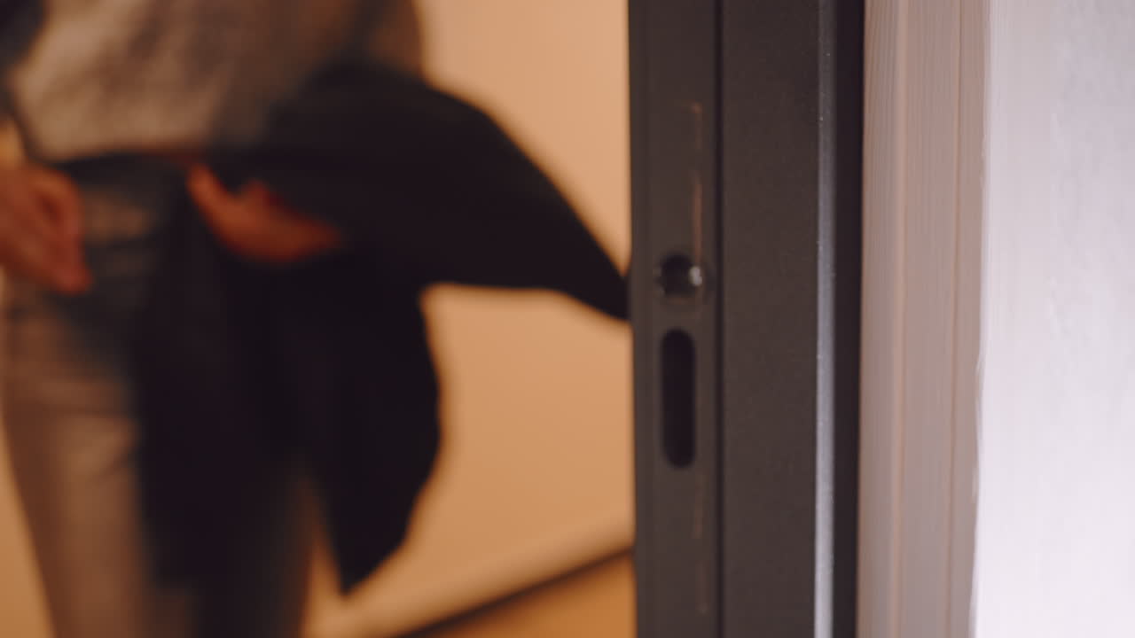 Close up of hand gripping door handle turning lock to open and step outside before closing door, capturing everyday action of leaving home with focus on gesture