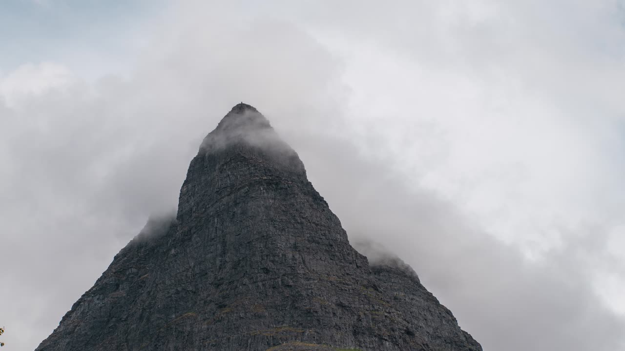 Beautiful time lapse of a large mountain peak at Innerdalstårnet, Norway. Clouds flying past the mountain peak, slowly zooming out.