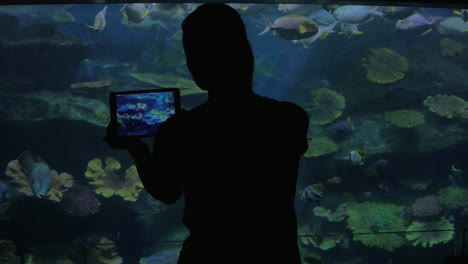 young woman in bangkok thailand at the oceanarium of siam ocean world take pictures on her tablet