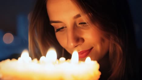 woman blowing out candles on birthday cake