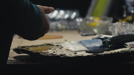 person makes mobile call before tossing phone onto shadowy work table