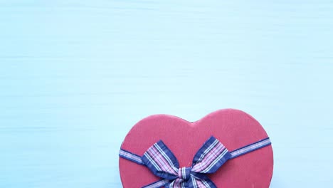 caja de regalo en forma de corazón en un guante azul
