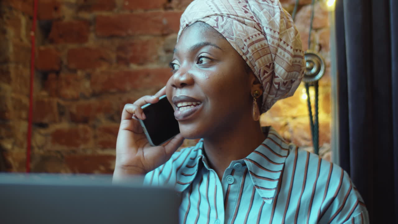 mujer afroamericana hablando por teléfono móvil en un café