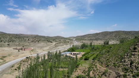 el dron ve las montañas verdes de paktia en afganistán, divididas por una carretera.