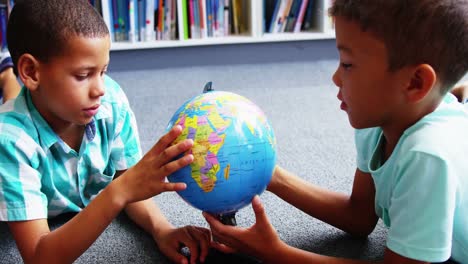 Schoolkids-looking-at-globe-in-library-at-school