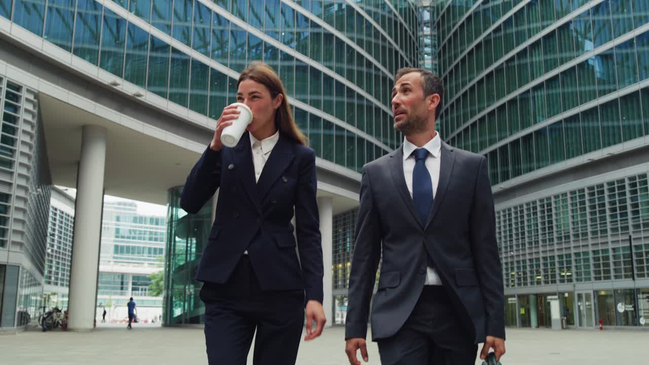 Cinematic shot of happy smiling business colleagues in formal apparel are walking satisfied with their work after leaving the offices. Concept of corporate, company, success, cooperation, teamwork.