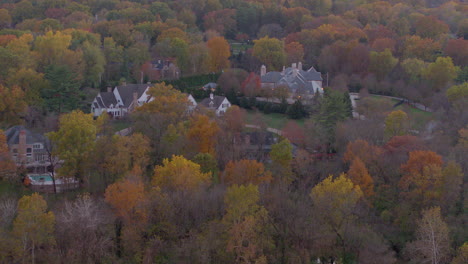 vista aérea de hermosas casas grandes enclavadas en árboles en color pico en otoño con una inclinación hacia un bonito cielo rosado y amarillo al atardecer