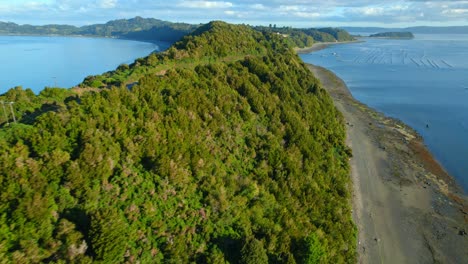 Flyover-virgin-beaches-in-the-narrow-channel-linking-Lemuy-Island-with-Detif-in-Chiloe,-car-tracking,-Chile