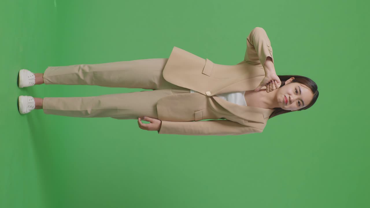 녹색 스크린 스튜디오에 서 있는 동안 엄지손가락을 내려놓은 아시아 사업가 여성의 몸매가 가득 차 있습니다.