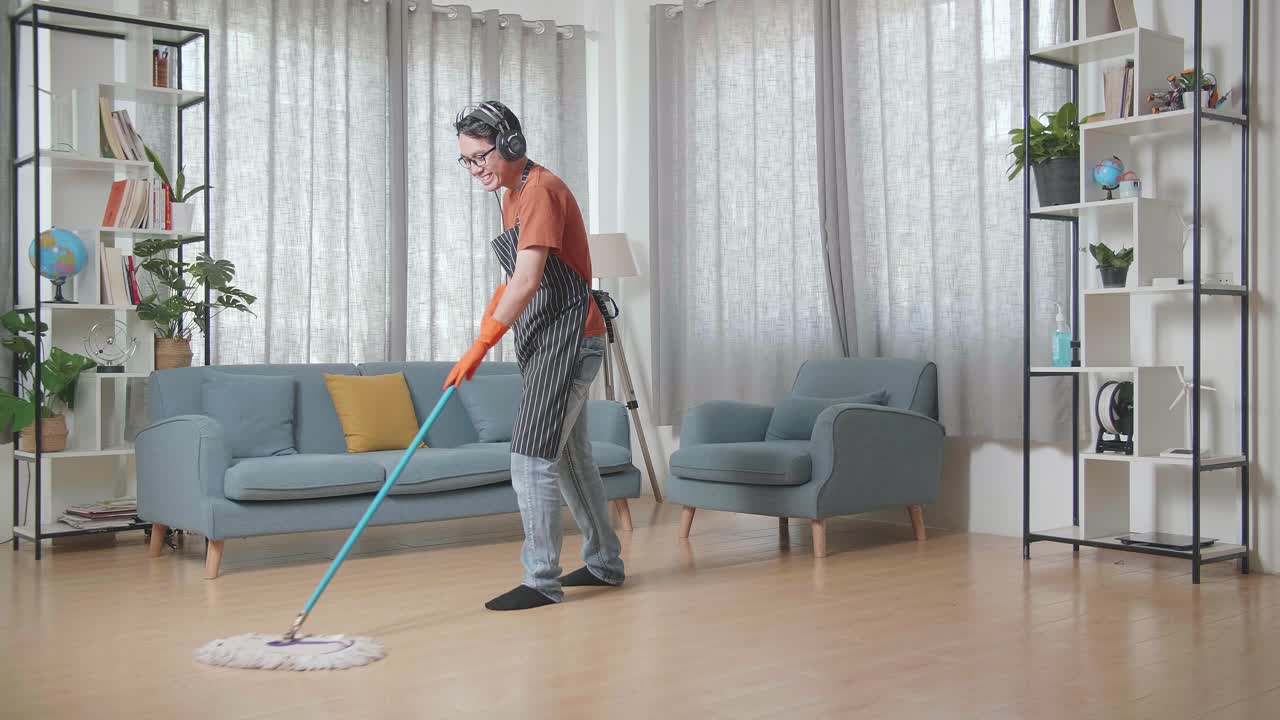 a un ama de casa asiático con un delantal le gusta limpiar el suelo en casa