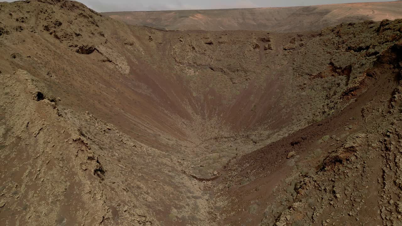 Dronie of volcano crater. Aerial view of volcano. Interior of a volcanic crater and lava outlet area. Canary Islands. Spain.