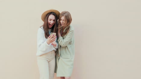 two young women laughing at a smartphone