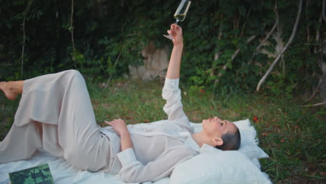 lady posing wine glass on picnic garden. relaxed woman lying blanket with drink