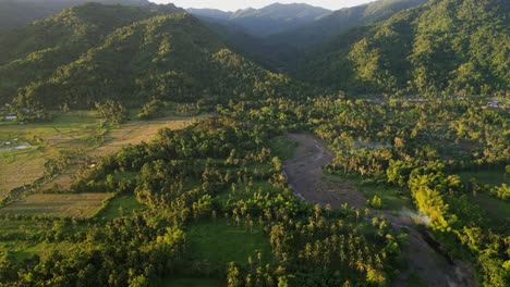 picturesque aerial flyover shot of lush tropical valley setting with mountainous backdrop during golden hour - catanduanes, philippines