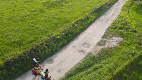 veduta aerea di un gruppo di tre pellegrini che camminano insieme su strada sterrata in giornata di sole