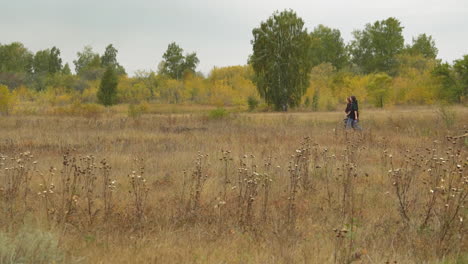 couple of girls walks on meadow near village under clear sky