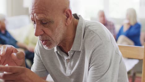 Sad-senior-biracial-man-crying-at-support-group-meeting-of-diverse-seniors,-copy-space,-slow-motion