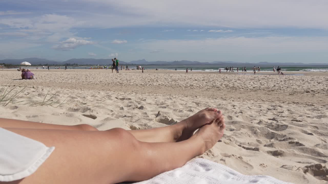 Beautiful tan feet relaxing on sandy beach, clear skyline ocean view Australia Oceania