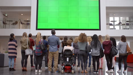 Studenten-Applaudieren-Auf-Einer-Großen-Leinwand-Im-Foyer-Der-Universität,-Rückansicht