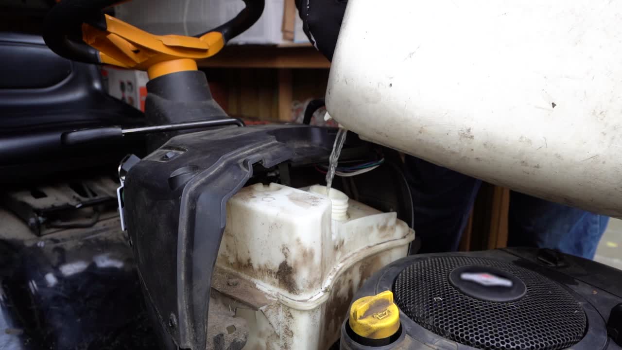 슬로우 모션 휘발유가 깎는 기계의 연료 탱크에 쏟아지고 있습니다.