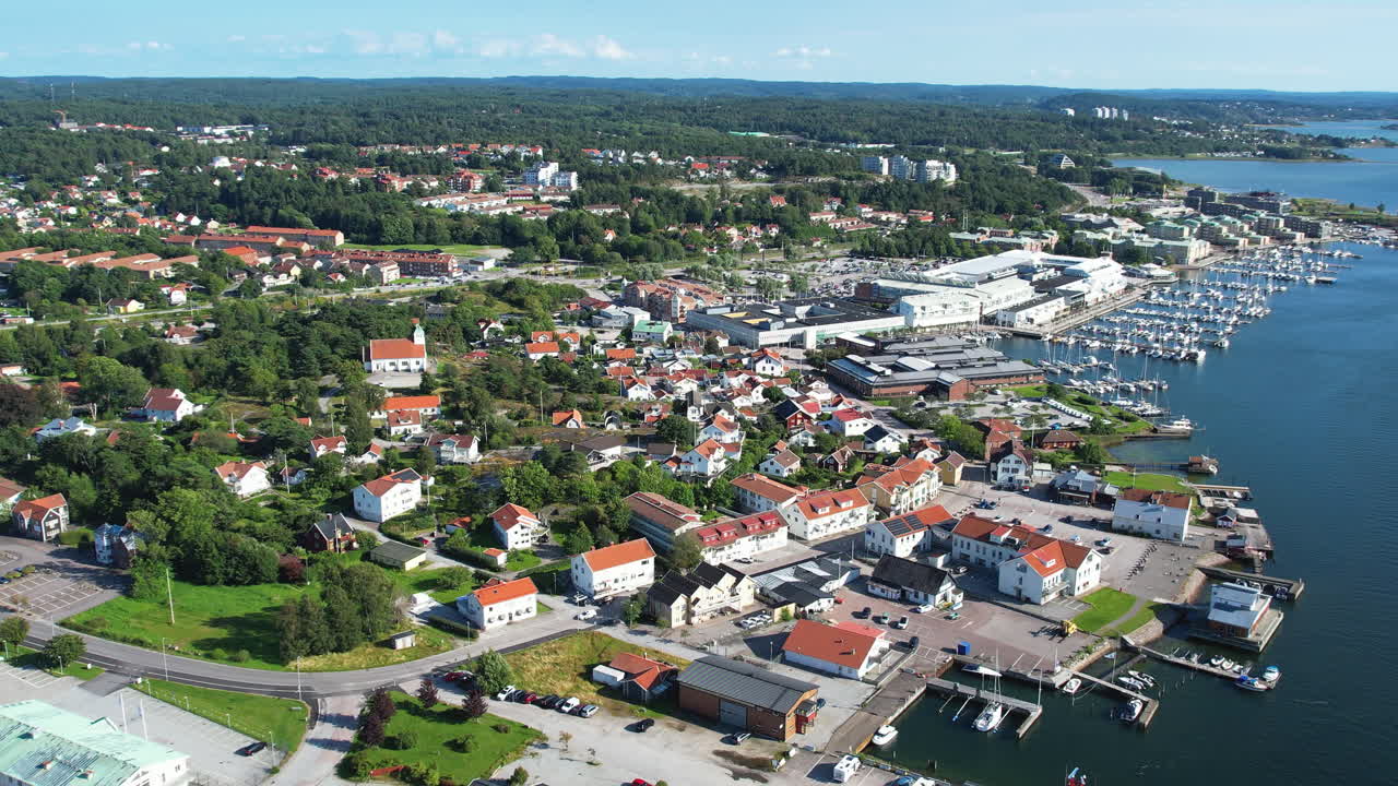 Pull out drone shot of Stenungsund harbor with boats, harbor and blue water in the day in Bohuslan, Sweden