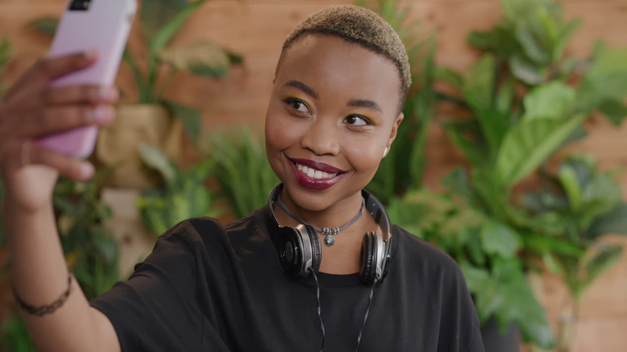retrato de una hermosa mujer afroamericana tomando una foto selfie usando la cámara de un teléfono inteligente sonriendo disfrutando de la tecnología del teléfono móvil compartiendo fotografía