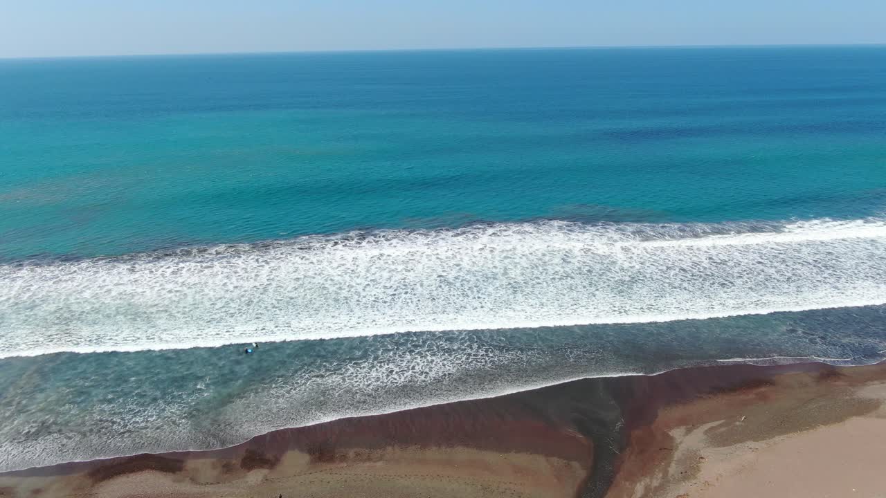 drone de playa de costa rica volando sobre la orilla y en el océano con un río abriéndose al agua en el océano pacífico en un día soleado