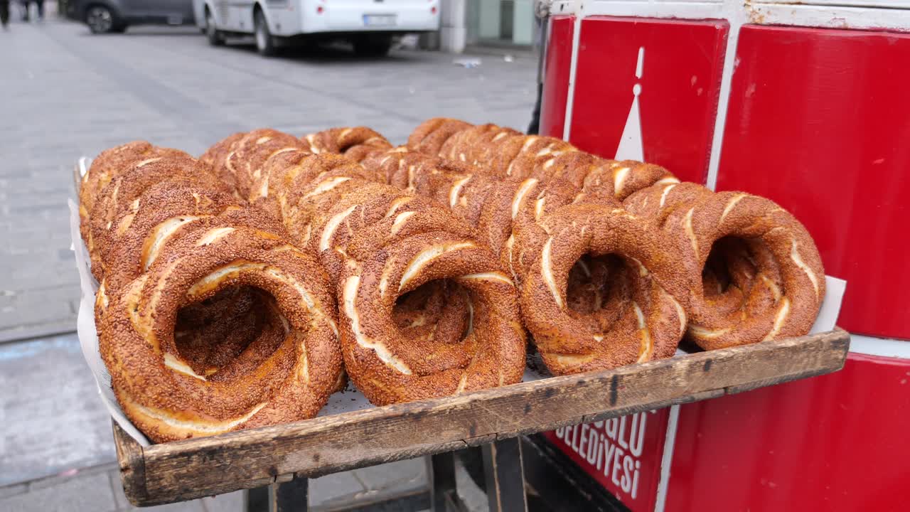 새로 구운 터키 시미트 (turkish simit) 가 길거리 카트 (street cart) 에 달려 있다.