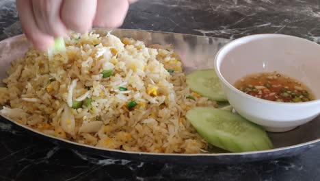 persona comiendo arroz frito con pepino y salsa