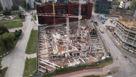 Toma-Aérea-De-Una-Bulliciosa-Obra-De-Construcción-En-Un-Entorno-Urbano-Con-Edificios-Y-Carreteras-Circundantes