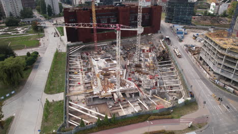 toma aérea de un bullicioso sitio de construcción en un entorno urbano con los edificios y carreteras circundantes