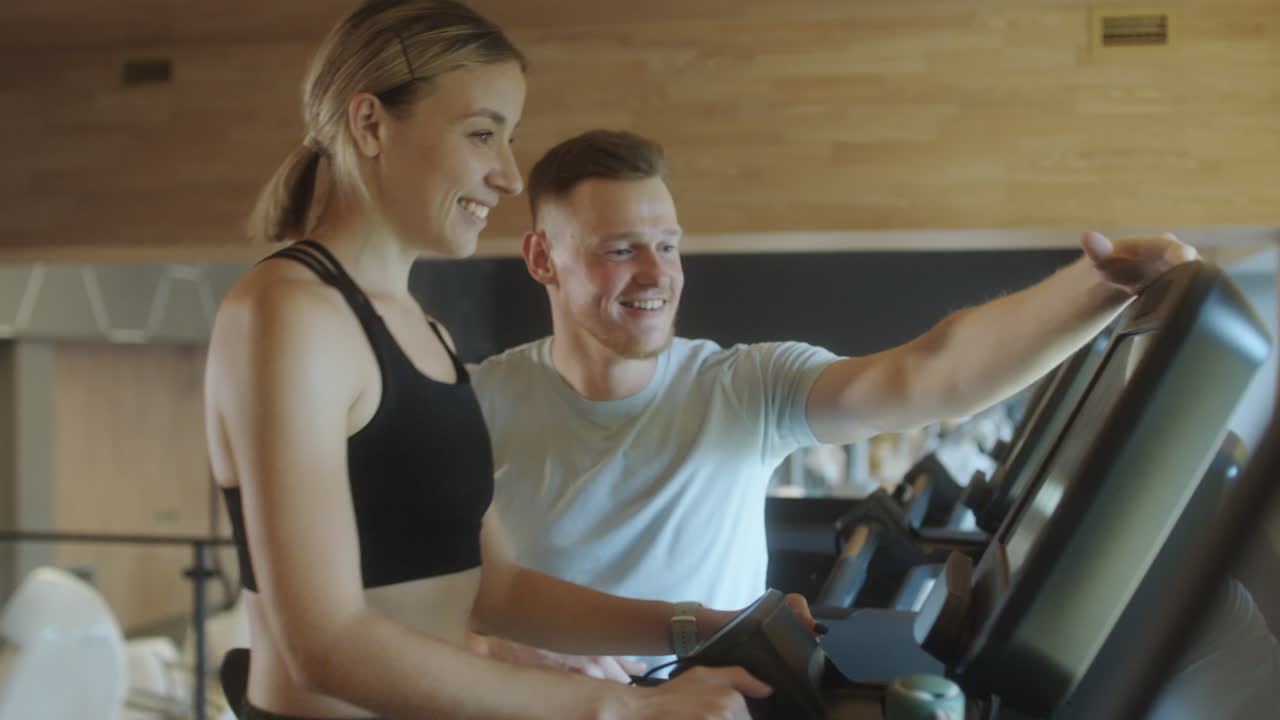 Woman Exercising on Gym Treadmill with Personal Trainer