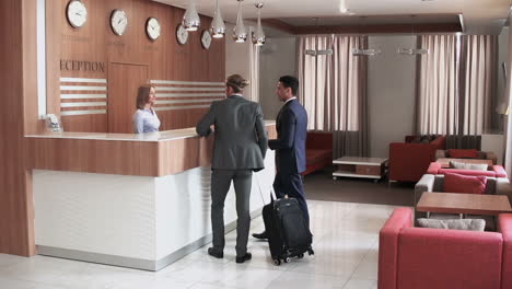 two businessmen check in at a hotel front desk