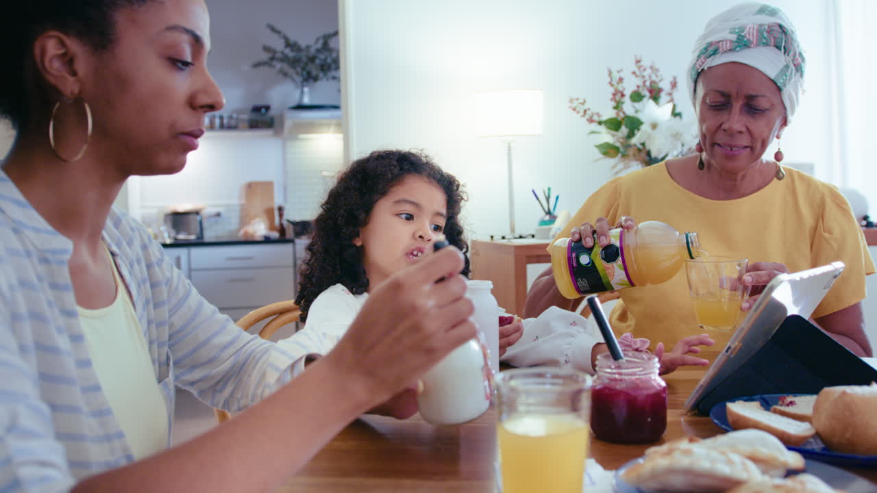 abuela afroamericana, madre e hija desayunando en casa