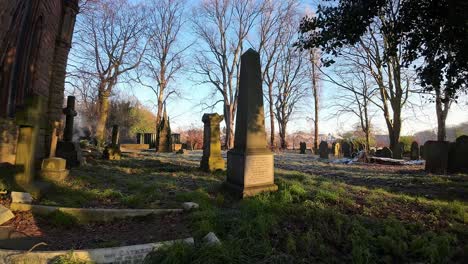 FPV-flying-around-headstones-in-snowy-autumn-sunrise-churchyard-cemetery-during-golden-hour