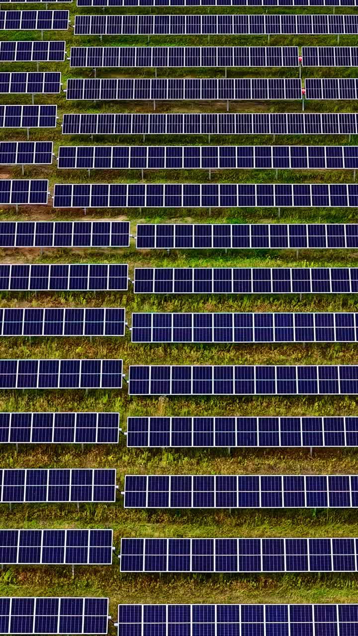 Drone che effettua una panoramica su un campo di pannelli solari, simmetria di una centrale elettrica fotovoltaica.
