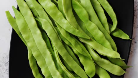 Black-ceramic-plate-with-fresh-green-bean-pods