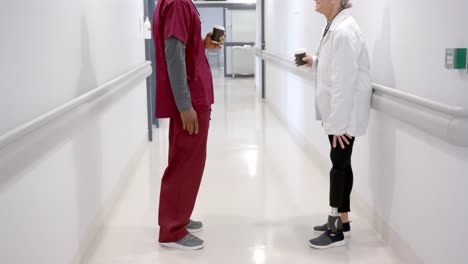 Diverse-male-and-female-doctors-in-discussion-drinking-coffee-in-hospital-corridor,-slow-motion