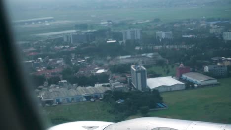 handheld shot taken from the window of a landing plane with a view of the cityscape