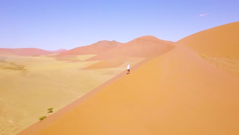 Aerial-over-a-man-hiking-in-the-rugged-desert-landscape-and-sand-dunes-near-Dune-45-in-Namibia-Africa-2