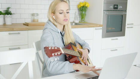 Girl-practicing-guitar-and-using-laptop-