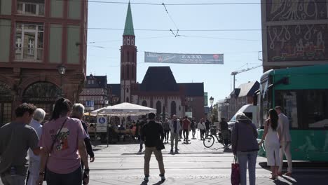 green tram and people on a city street in frankfurt