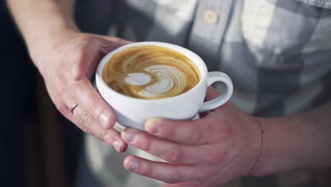 professional barista pouring milk foam over coffee into white cup creating perfect cappuccino and making a nice pattern