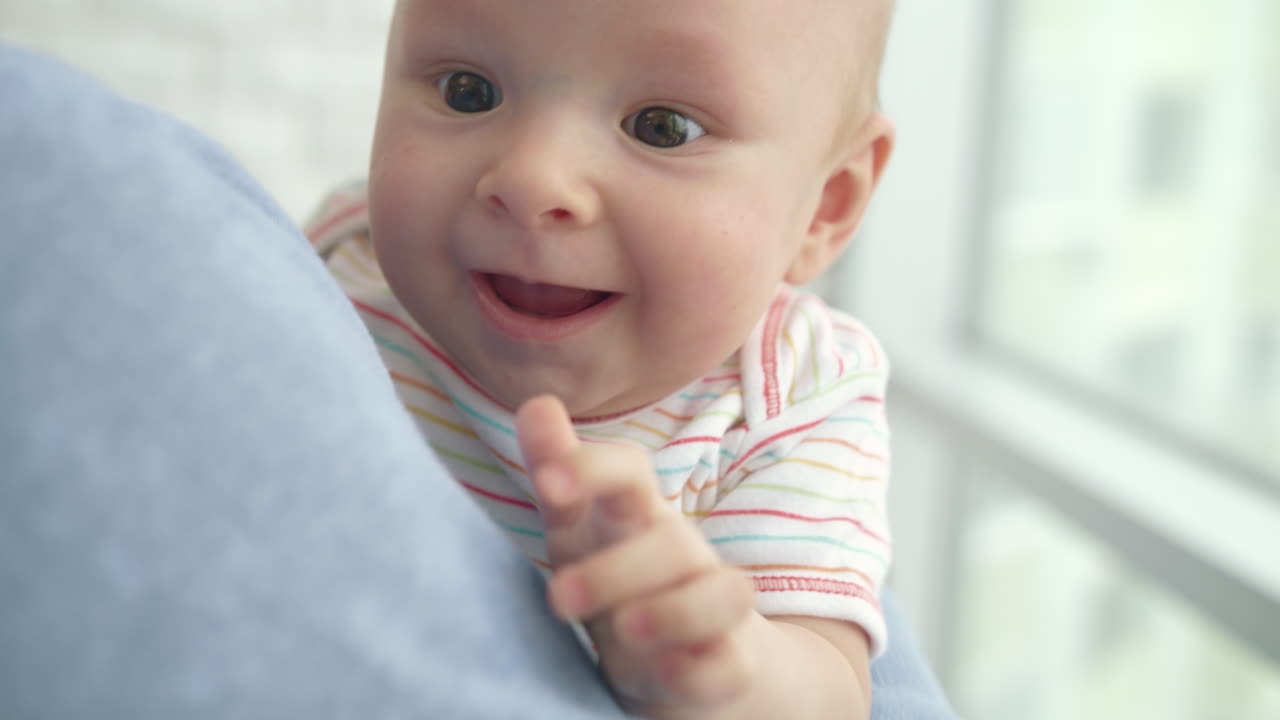 아빠의 손에 있는 작은 아이. 아빠가 아들을 안아주는 아기. 귀여운 아기가 주위를 둘러보고 있다.