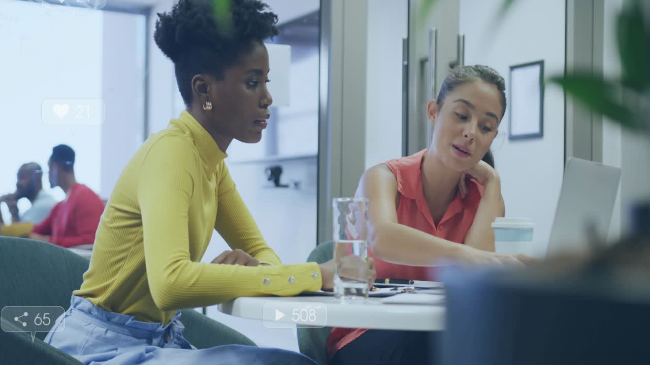 Two women pointing at laptop and phone, initiating social media overlays while analyzing metrics