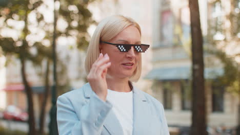 feliz mujer de negocios rica y madura poniéndose gafas de sol de vida de matón mostrando dinero en dólares en la calle de la ciudad